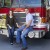 Engaged couple sitting on the front of a firetruck